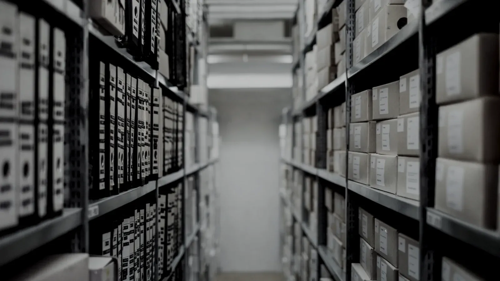 A corridor of archive shelving stacked with identical boxes, receding into the dark