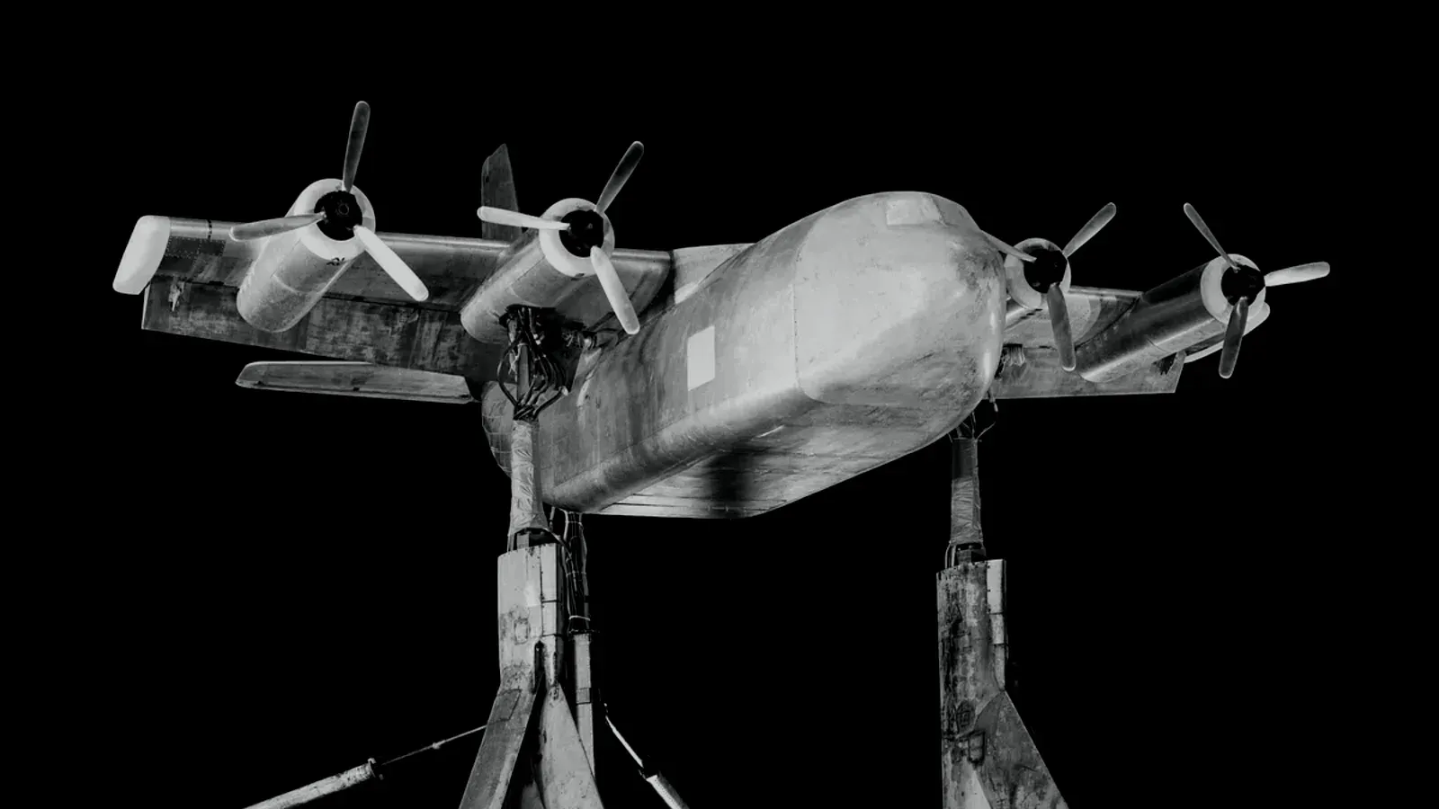 A scale aircraft model mounted on a rig in a wind tunnel against a black background